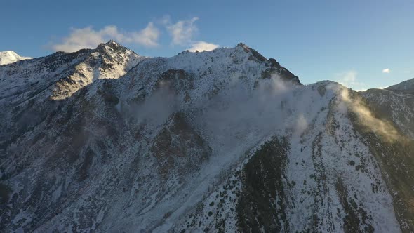 Mountain tops covered in snow with thin clouds rolling off