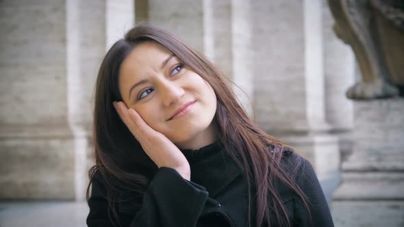 young brunette woman putting her hand in her face and looks dreamily.