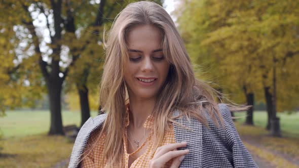 Smiling Caucasian Girl Putting on Checkered Jacket and Looking Away