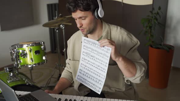 Man Conducts Piano Lesson Via Laptop Showing Music Sheet