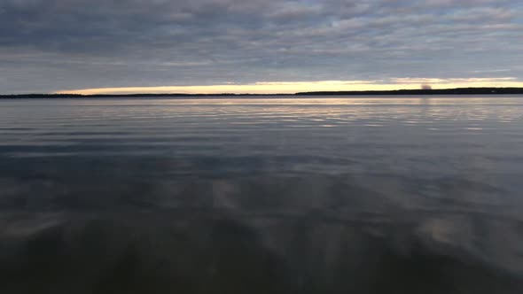 Droneing fast over calm water on a lake during sunset