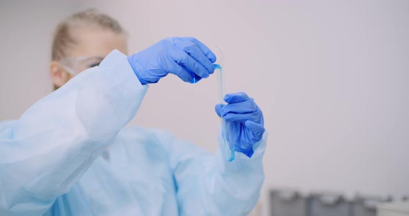 Female Scientist Holding Tubes and Flask with Liquid in Hands