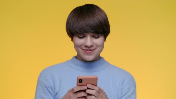 Pleasant Woman Using Smartphone Over Yellow Background