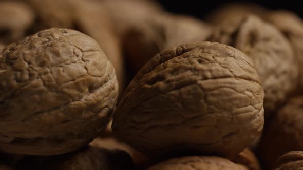 Cinematic, rotating shot of walnuts in their shells on a white surface - WALNUTS