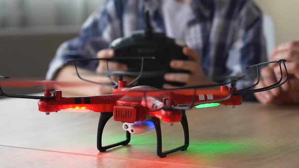 Boy With Sparkling Eyes Operates Drone, Uses Remote Control, Father Sits Near