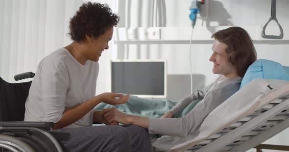 Diverse Couple After Accident Talking in Hospital Ward