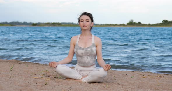 Woman practicing yoga outside in lotus pose on beach