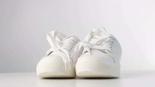 Pair of White Leather Sneakers Spinning on a White Background