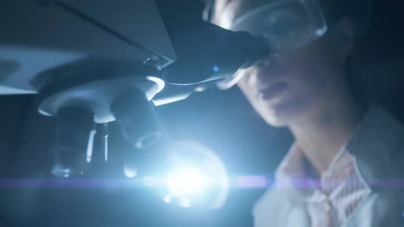 A Woman Scientist is Looking Into Microscope Biochemical Research