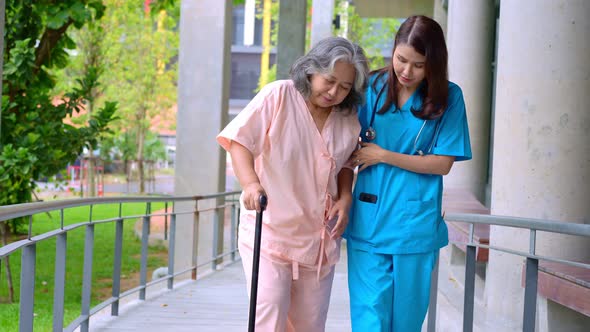 Doctor help old elderly Asian woman uses a walker and walking for physical therapy in the hospital.