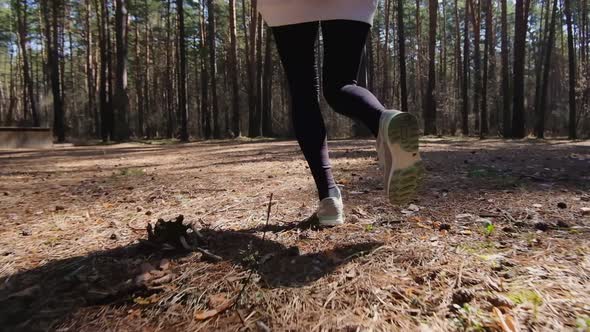 Rear view of an active sportswoman running in a city park, fashionable sports leggings, sneakers.