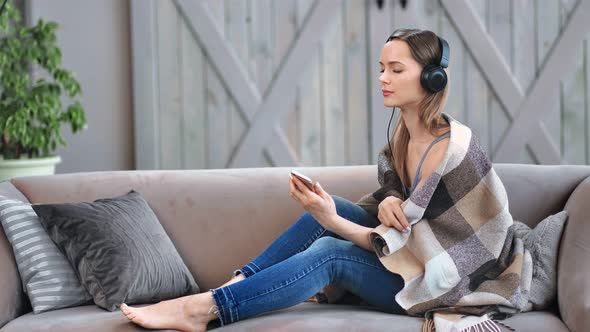 Joyful Barefoot Female Enjoying Audio Sound in Earphones Using Mobile