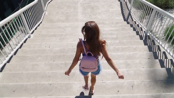 Happy Playful Woman Coming down the stairs with a backpack. Slow motion