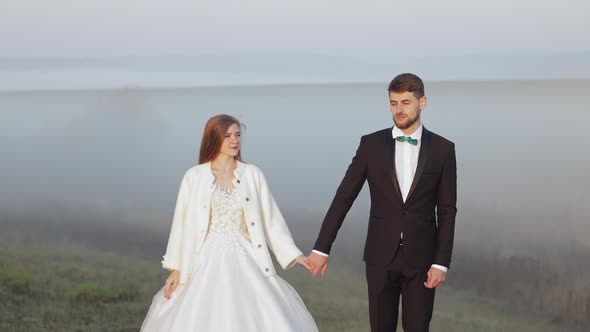 Newlyweds. Caucasian Groom with Bride on the Morning Field. Fog. Wedding Couple