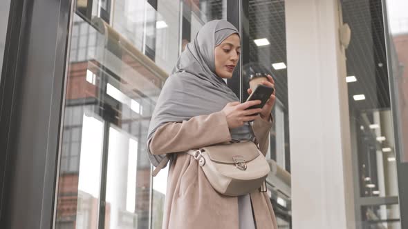 Arabic Woman Scrolling on Smartphone Indoors