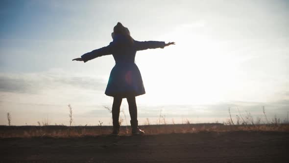 Silhouette Girl Child Stands in a Field at Sunset Wide Open Arms. The Concept of Childhood Dreams.