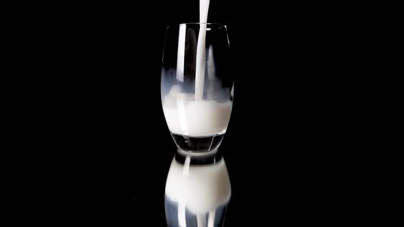 Close up shot of pouring vegan rice milk in a glas in slow motion on a shiny and reflective undergro