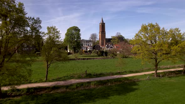 Aerial approach of Dutch painterly picturesque Amerongen village town passing over countryside meado