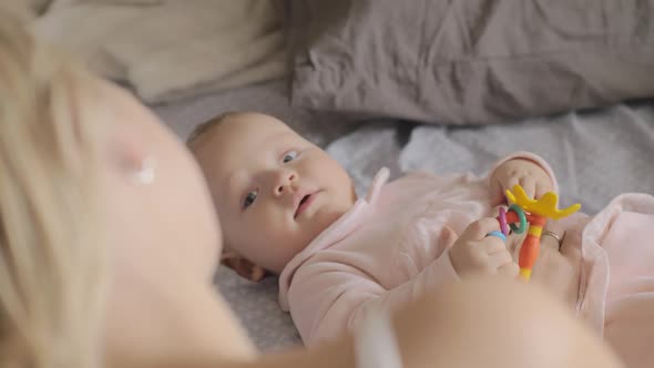 A Cute Baby Girl Lying on a Back and Smiling To Her Mother