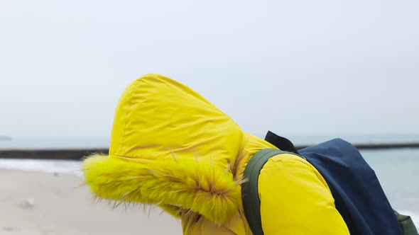 Adult Woman in a Warm Yellow Jacket with a Backpack Uses a Protective Medical Mask Walking Walks