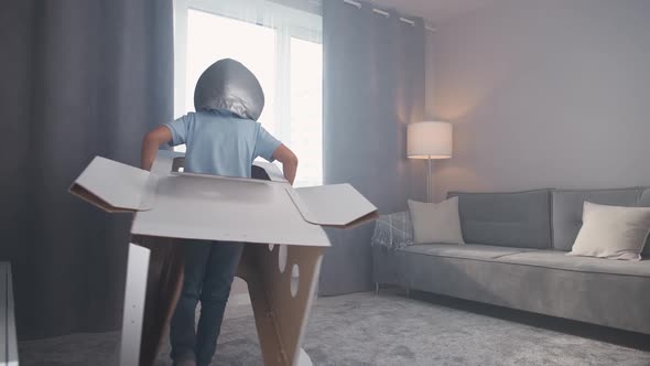 Boy in an Astronaut Costume Plays with a Cardboard Space Shuttle Runs Around the Room  Slow Motion