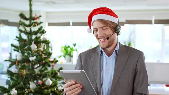 Handsome Cheerful Young Businessman Wearing Christmas Hat Holding Tablet Having Video Call Over