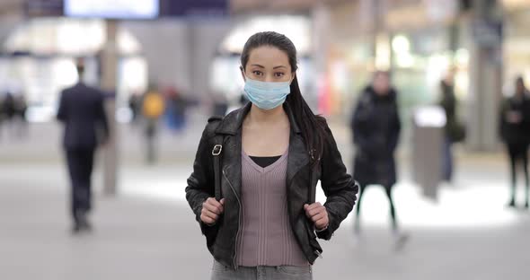 Chinese woman at train station in London wearing face mask to protect from sm