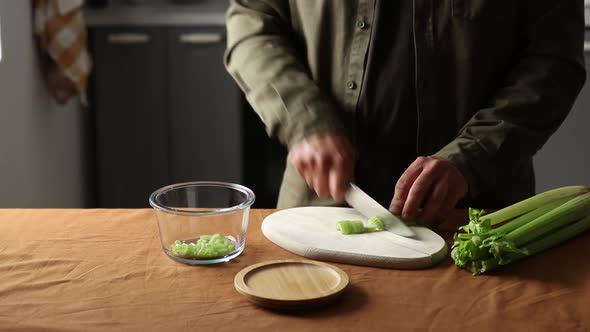 vegetarian man cuts Celery on a chalkboard in the kitchen with a knife