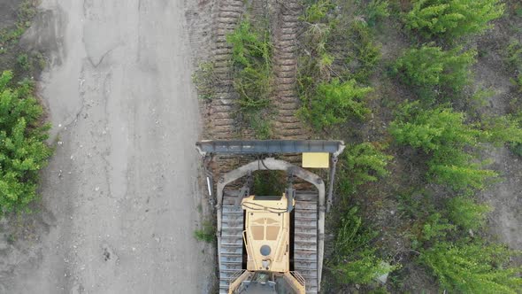 Top Aerial View on Tracked Bulldozer Rides on Sandy Road at Construction Site