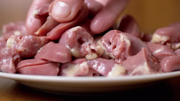 Female Hand Mixing Fresh Raw Peeled Chicken Hearts in a Plate