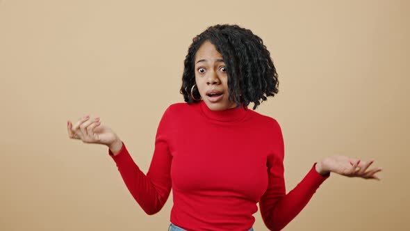 Young Black Woman in Red Sweater Feeling Unguilty Outstretching Arms and Shrugging Shoulders in