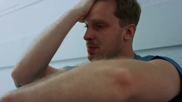 Upset Doctor Holding Hand on Face Sitting Floor Hospital Corridor Closeup