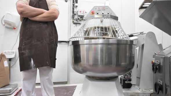 Portrait of Confident Baker in Apron Crossing Hands Looking at Camera Smiling with Automatic Mixer