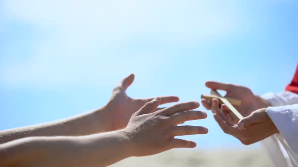 Priest Hands Giving Wooden Cross to Man, Sharing Religious Faith and Hope