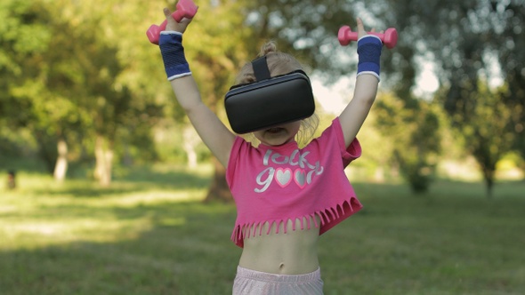 Athletic Child Girl in VR Headset Helmet Making Fitness Workout Exercises with Dumbbells in Park