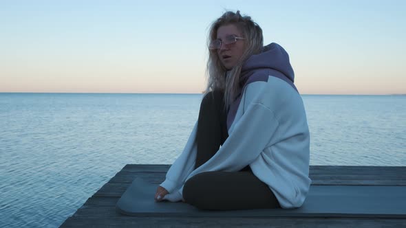 Girl sitting on the pier and talking. Slow motion