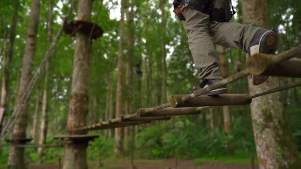 Shot of a Little Boy in a Safety Harness Climbs on a Route in Treetops in a Forest