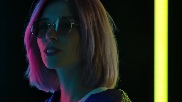 Portrait of a Young Stylish Woman in Sunglasses Looking at the Camera Chewing Gum and Blowing