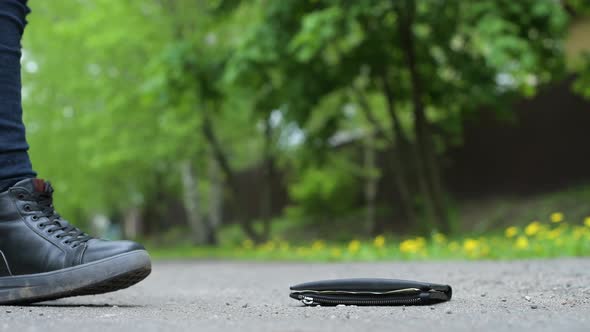 Side view of a girl finds a lost wallet on the street