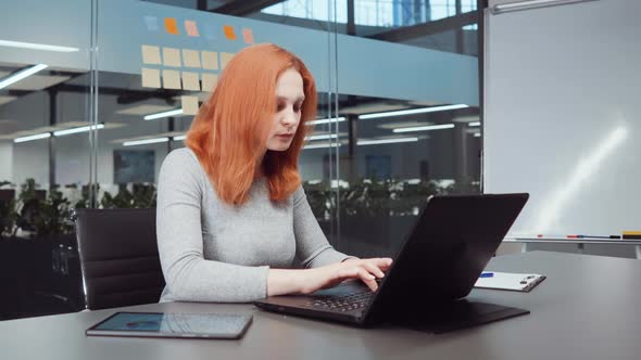 Red Haired Woman Typing Report in Business Office