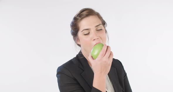 Woman eating a big green apple on a white studio background