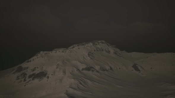 Dramatic Dark Rocky Mountain with Patches of Snow in Storm