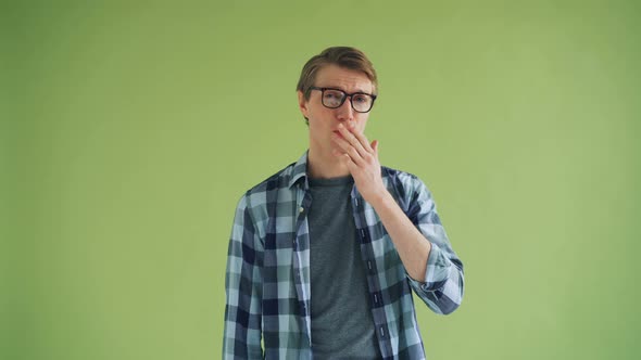 Portrait of Smiling Young Man Sending Air Kiss and Winking on Green Background