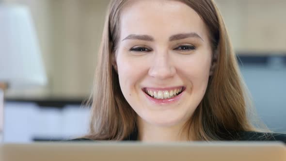 Woman Smiling Toward Camera while Working on Laptop