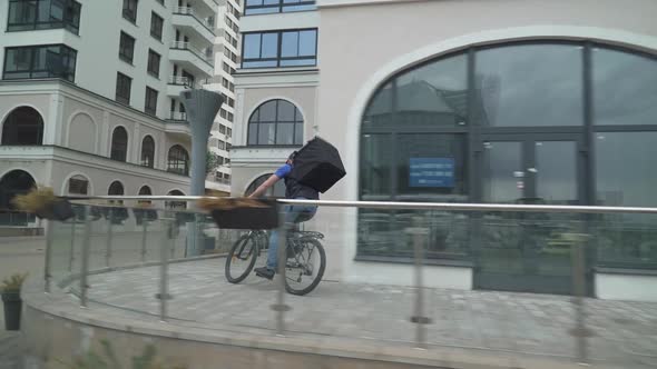 Courier with a Thermo Backpack Rides a Bicycle to the Customer Food Delivery in the Conditions