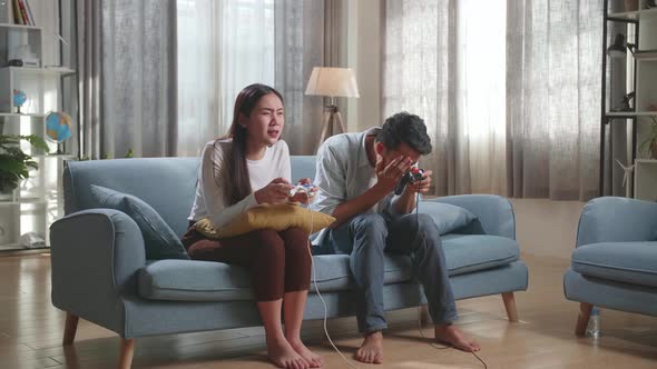 Young Asian Couple With Joystick Play Video Game On Tv And Lost