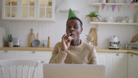 Cheerful Man with Birthday Cap Talks Via Videocall on Laptop