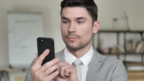 Businessman Excited for Results on Smartphone