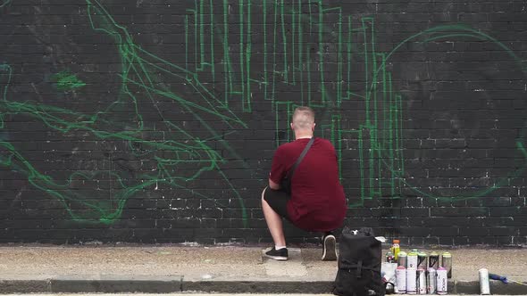 graffiti artist making a sketch while people crossing in foreground