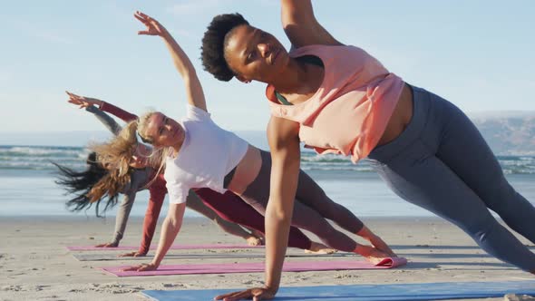 Group of diverse female friends practicing yoga at the beach